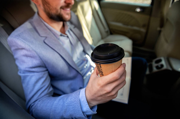 Man drinking coffee on the back seat of the car - Foto, Imagen