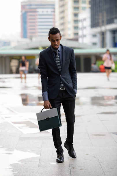 Νεαρός αφρικανική επιχειρηματίας με χαρτοφύλακα, το περπάτημα στο δρόμο της πόλης - Φωτογραφία, εικόνα