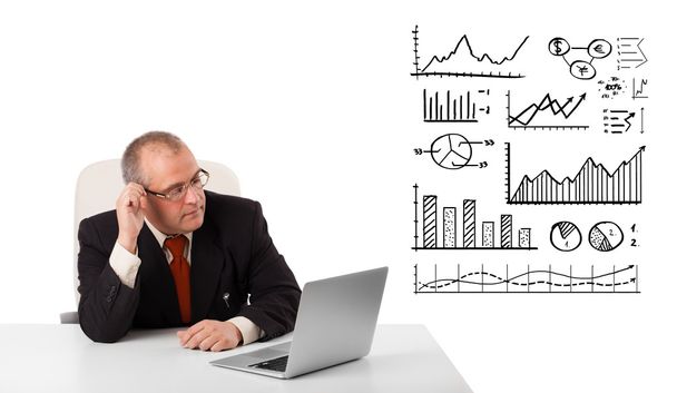 businessman sitting at desk with graphs and laptop - Foto, Imagen