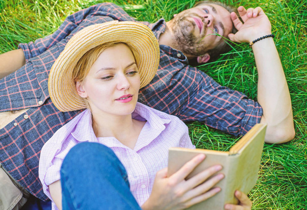 Man and girl lay on grass reading book. Couple soulmates at romantic date. Couple in love spend leisure reading book in park. Family enjoy leisure with poetry or literature book grass background - Photo, Image