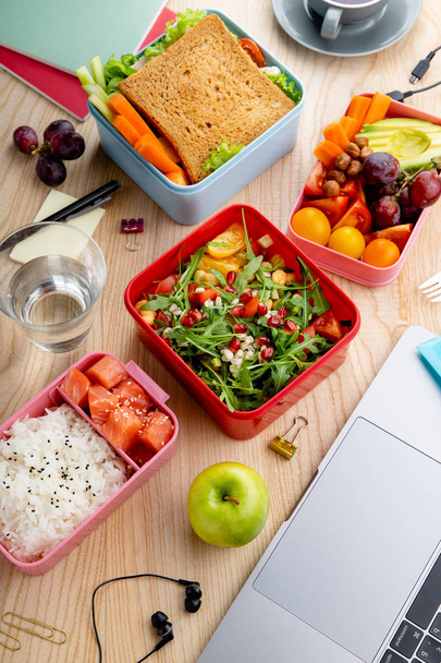  healthy lunch dishes in bento boxes near laptop on wooden table, Daily office lunch concept - Foto, Bild