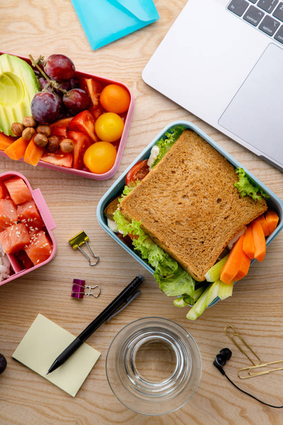  healthy lunch dishes in bento boxes near laptop on wooden table, Daily office lunch concept - Foto, imagen