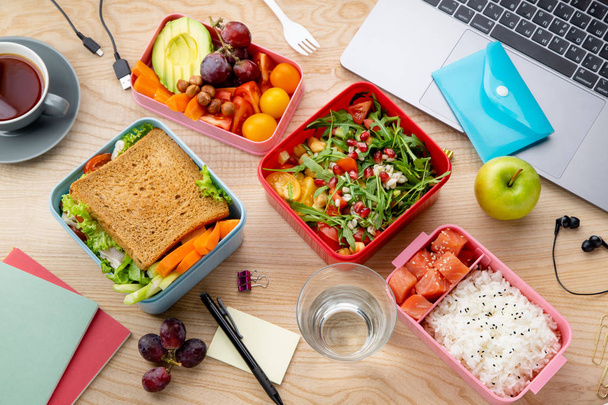  healthy lunch dishes in bento boxes near laptop on wooden table, Daily office lunch concept - Foto, Imagem
