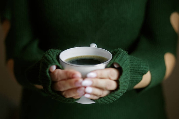 Ένα φλιτζάνι ζεστό καφέ στα χέρια. Έννοια ποτά, τρόπος ζωής, εργασίας, φόντο. - Φωτογραφία, εικόνα