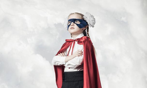 Little confident child in mask and cape plays cool superhero - Фото, изображение