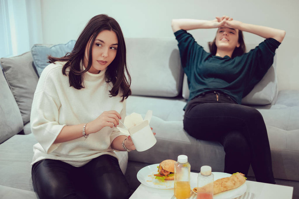 Mädchen isst Pasta, während ihre Freundin sich ausruht - Foto, Bild