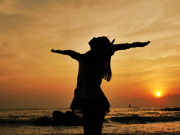 Dziewczyna Silhouette, podnosząc ręce na plaży w wschód słońca. - Zdjęcie, obraz