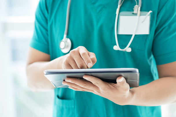 K nepoznání muž v lékařských uniformě pomocí moderní tablet stoje v nemocnici - Fotografie, Obrázek