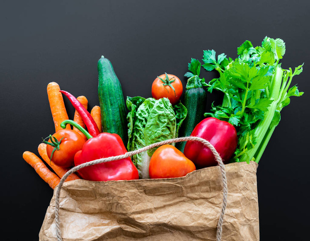 свежие органические овощи в коричневом бумажном пакете на темном фоне стола
 - Фото, изображение