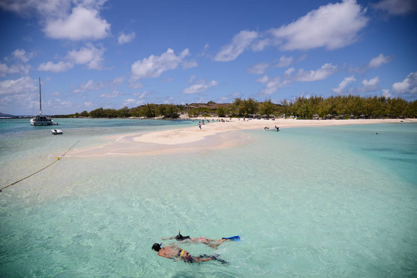 hermosa playa con aguas turquesas y dos personas snorkeling
 - Foto, imagen