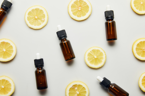 Flat lay with essential oil in bottles and lemon slices on grey background - Φωτογραφία, εικόνα