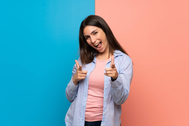Genç kadın önüne işaret ve gülümseyen pembe ve mavi duvarın üzerinden - Fotoğraf, Görsel