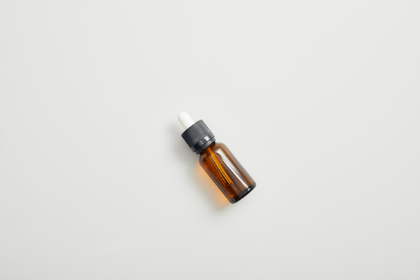 Top view of brown bottle with essential oil on grey background - Foto, afbeelding