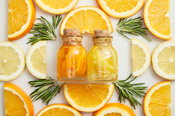 Flat lay with glass bottles and citrus slices with rosemary on white background - Photo, Image