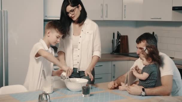 Молода щаслива сім'я готує вечерю разом на кухні
 - Кадри, відео