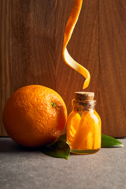 Orange und ätherisches Bio-Öl in Glasflasche auf Holzgrund - Foto, Bild