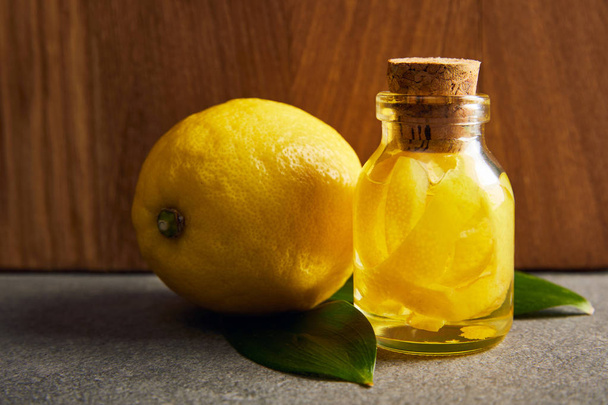 Citron entier avec bouteille d'huile essentielle à la surface sombre
 - Photo, image