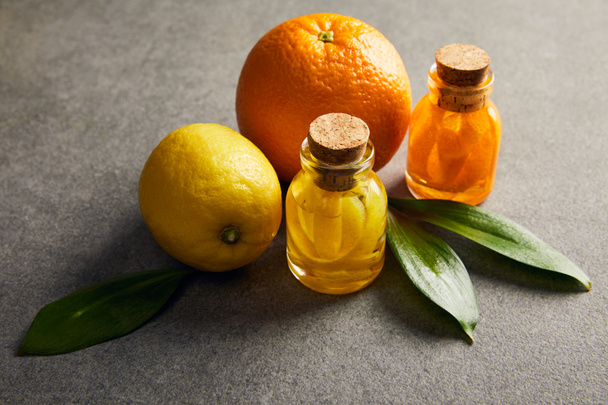 Bottles of essential oil with lemon and orange on dark surface - Φωτογραφία, εικόνα