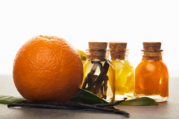 Garrafas de óleo essencial com laranja e baunilha sobre fundo branco
 - Foto, Imagem