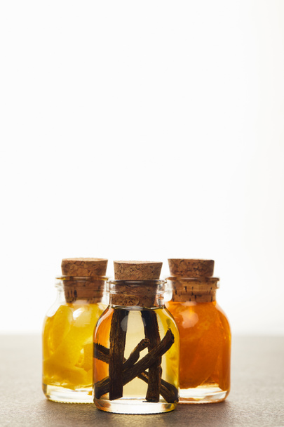 Glasflaschen mit ätherischem Öl mit geschnittenen Früchten auf weißem Hintergrund - Foto, Bild