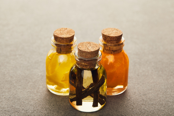 Botellas de vidrio de aceite esencial con frutas cortadas y picantes en la superficie oscura
 - Foto, Imagen