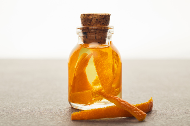 Glasflasche mit ätherischem Bio-Öl mit orangefarbenen Stücken auf weißem Hintergrund - Foto, Bild