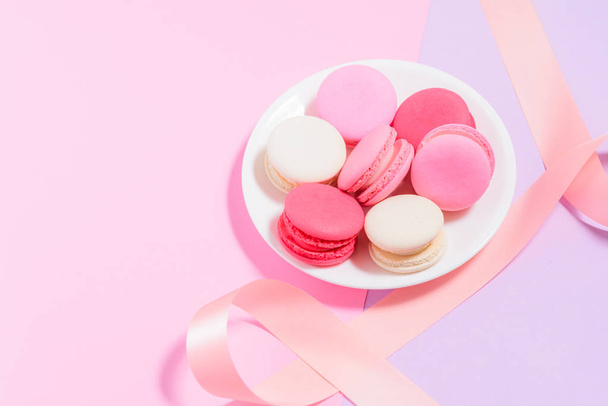 Macarrones coloridos caseros o macaron en plato blanco con rosa
  - Foto, imagen
