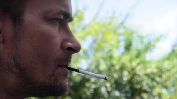 muž s vážnou tváří kouří v pomalém pohybu. - Záběry, video