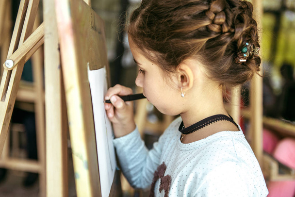 Young girl drawing on a canvas with easel - Photo, Image