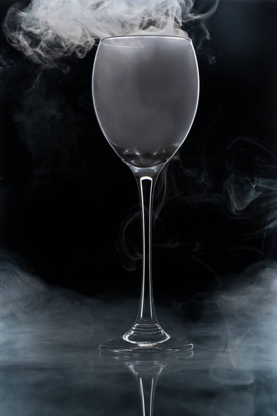 Closeup glass with white fog at dark background. Chemical reaction of dry ice with water. - Foto, Imagen