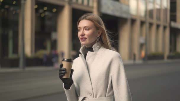 Attractive woman holding a cup of coffee waiting for the taxi - Video