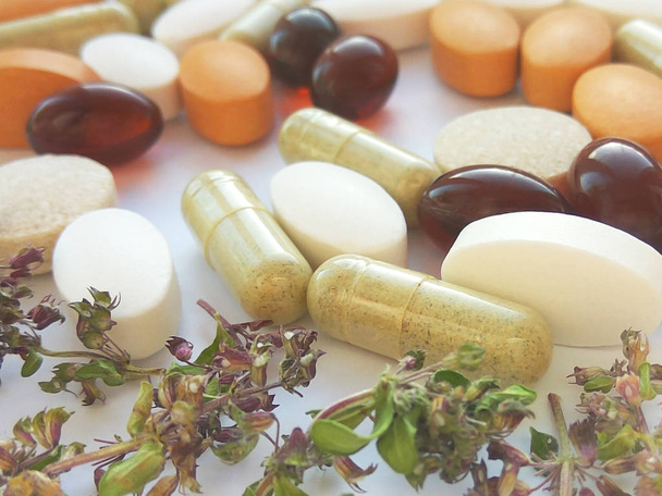 Kräutermedizin-Pillen mit trockenen natürlichen Kräutern auf weißem Hintergrund. Konzept der Kräutermedizin und Nahrungsergänzungsmittel, biologisch aktive Zusatzstoffe und Vitamine. Nahaufnahme - Foto, Bild