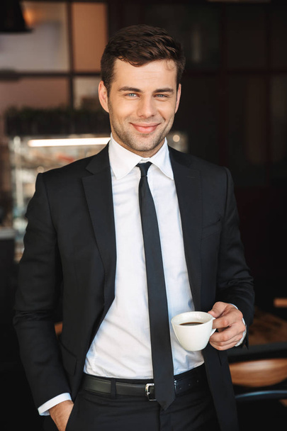 Handsome young businessman in formal clothes indoors in cafe drinking coffee. - Fotoğraf, Görsel
