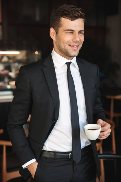 Handsome young businessman in formal clothes indoors in cafe drinking coffee. - Foto, Imagem