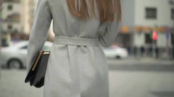 Ελκυστική γυναίκα, ντυμένη στο παλτό περπάτημα στροφή γύρω από χαμογελαστός και κουνώντας ένα χέρι - Πλάνα, βίντεο