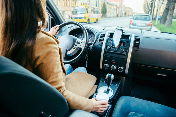 Kobieta, prowadzenie samochodu i picia kawy. Nawigacja za pomocą telefonu - Zdjęcie, obraz