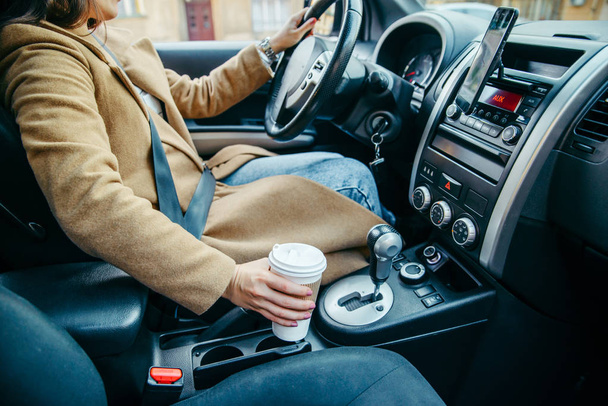 de kop van de vrouw hand nemen met koffie in de auto. Close-up. gewas - Foto, afbeelding