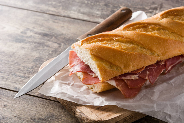 Spanish serrano ham sandwich on wooden table. - 写真・画像