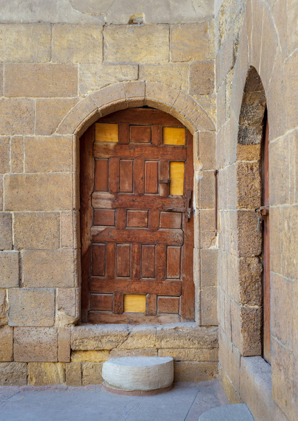 Régi, fából készült ajtó keretezi boltíves tégla kőfal a Courtyard al Razzaz vendégház a Darb al Ahmar district, régi Kairó, Egyiptom - Fotó, kép