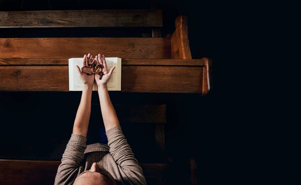Christian woman praying in church. Hands crossed and Holy Bible on wooden desk. Background - Φωτογραφία, εικόνα