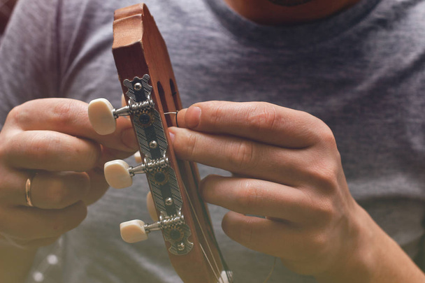 Крупним планом перегляд процесу зміни струн на акустичній гітарі шиї
 - Фото, зображення