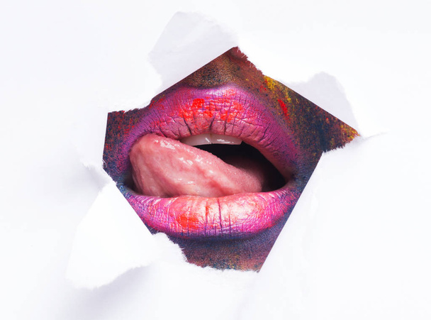 Young woman playing with tounge in paper hole - Foto, immagini