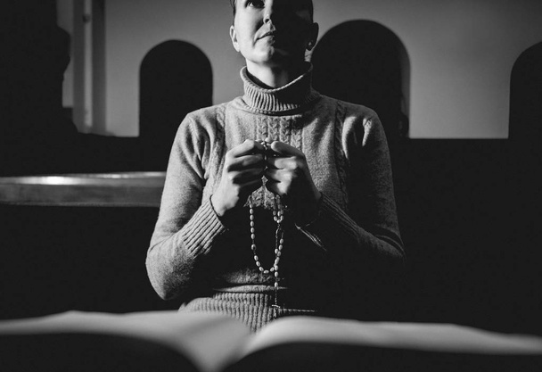 Donna cristiana che prega in chiesa. Mani incrociate e Sacra Bibbia sulla scrivania di legno. Contesto
 - Foto, immagini