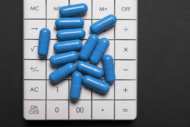 Modré pilulky jsou v kalkulačce. Koncept prodeje pilulek. Detailní záběr - Fotografie, Obrázek