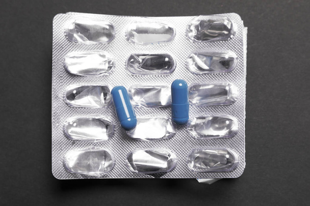 Blue pills on empty package on a black background - Photo, Image