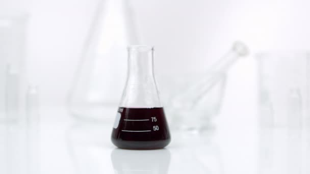 Panning view of beaker with liquid in it on white. - Video, Çekim