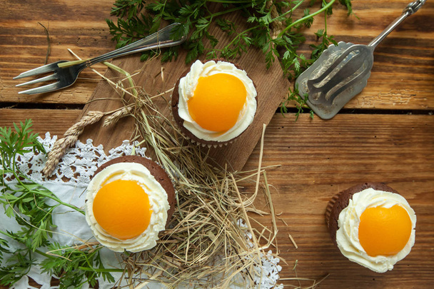Cupcake di Pasqua su sfondo di legno con pesca sembra un uovo fritto
 - Foto, immagini
