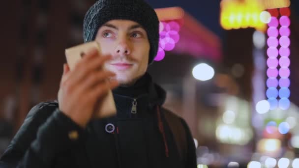 Ο άνθρωπος απαντά στην εισερχόμενη κλήση σε μια νυχτερινή πόλη - Πλάνα, βίντεο