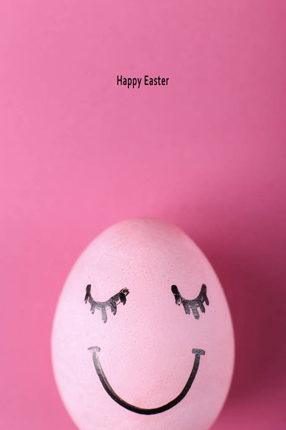 Pink egg with painted smiles. Happy Easter concept greeting card design. - Foto, Imagen