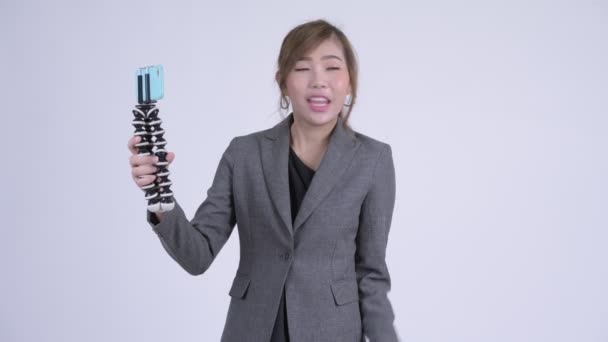 Young happy Asian businesswoman vlogging and showing phone - Séquence, vidéo
